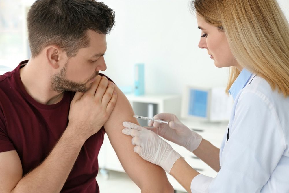 A Doctor Is Giving a Man an Injection in His Arm — Health Hub Mackay in Mackay, QLD