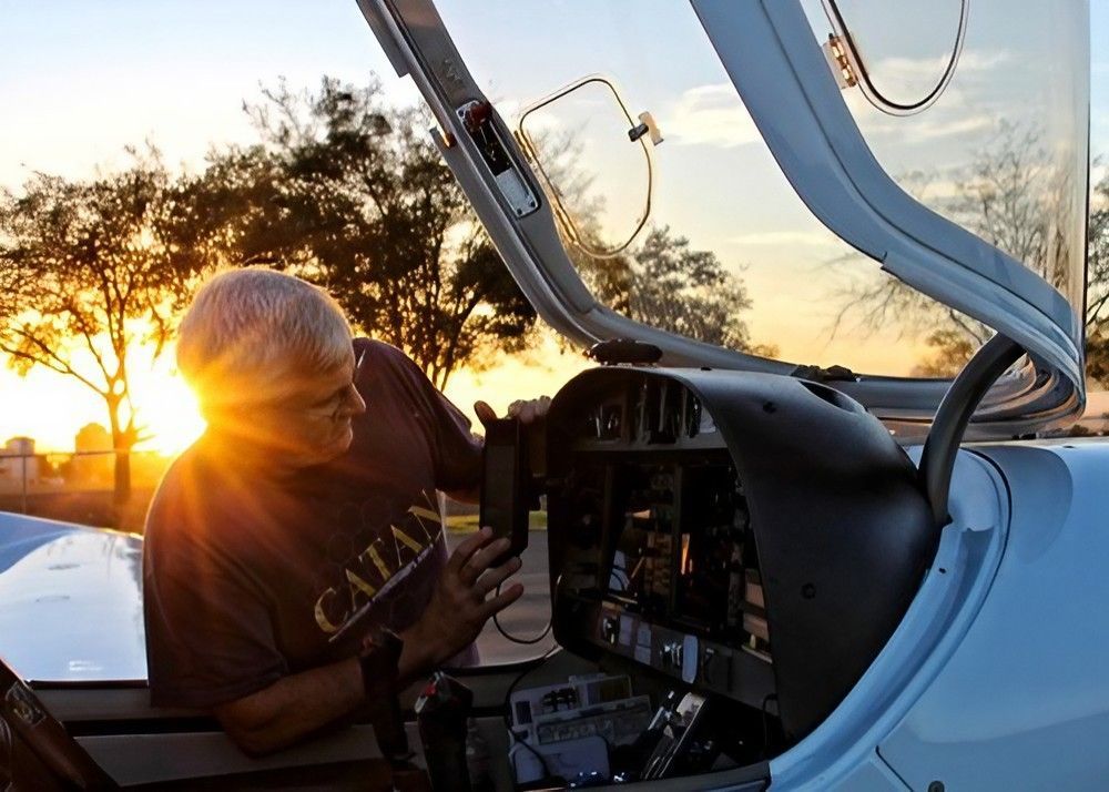 A Man in A Catan Shirt Sits in The Cockpit of An Airplane — Health Hub Mackay in Mackay, QLD