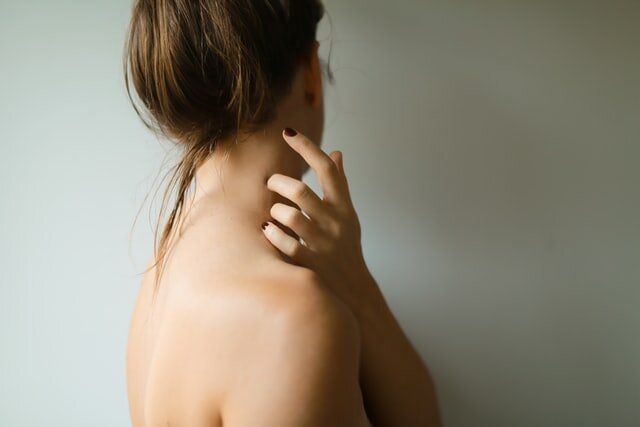A Woman Is Scratching Her Neck With Her Hand — Health Hub Mackay in Mackay, QLD
