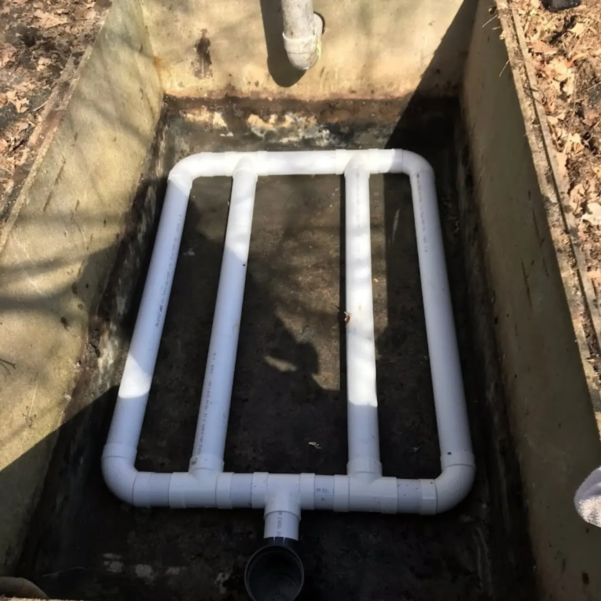 Affordable Waste Services - A white pipe is in a hole in the ground