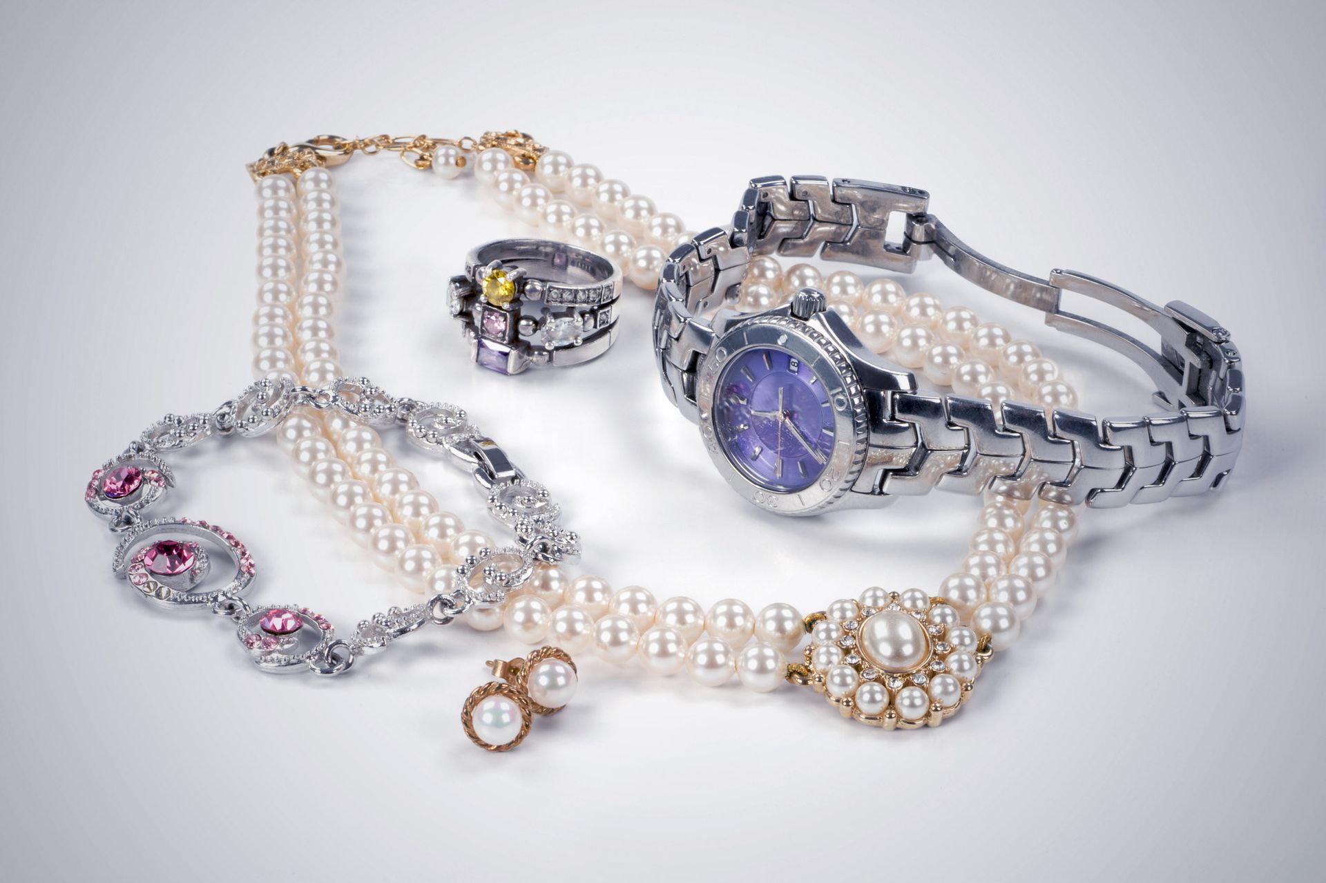 Jewelry and wristwatch: a ring, pearl necklaces, bracelet, earrings, and silver watch with a blue face.