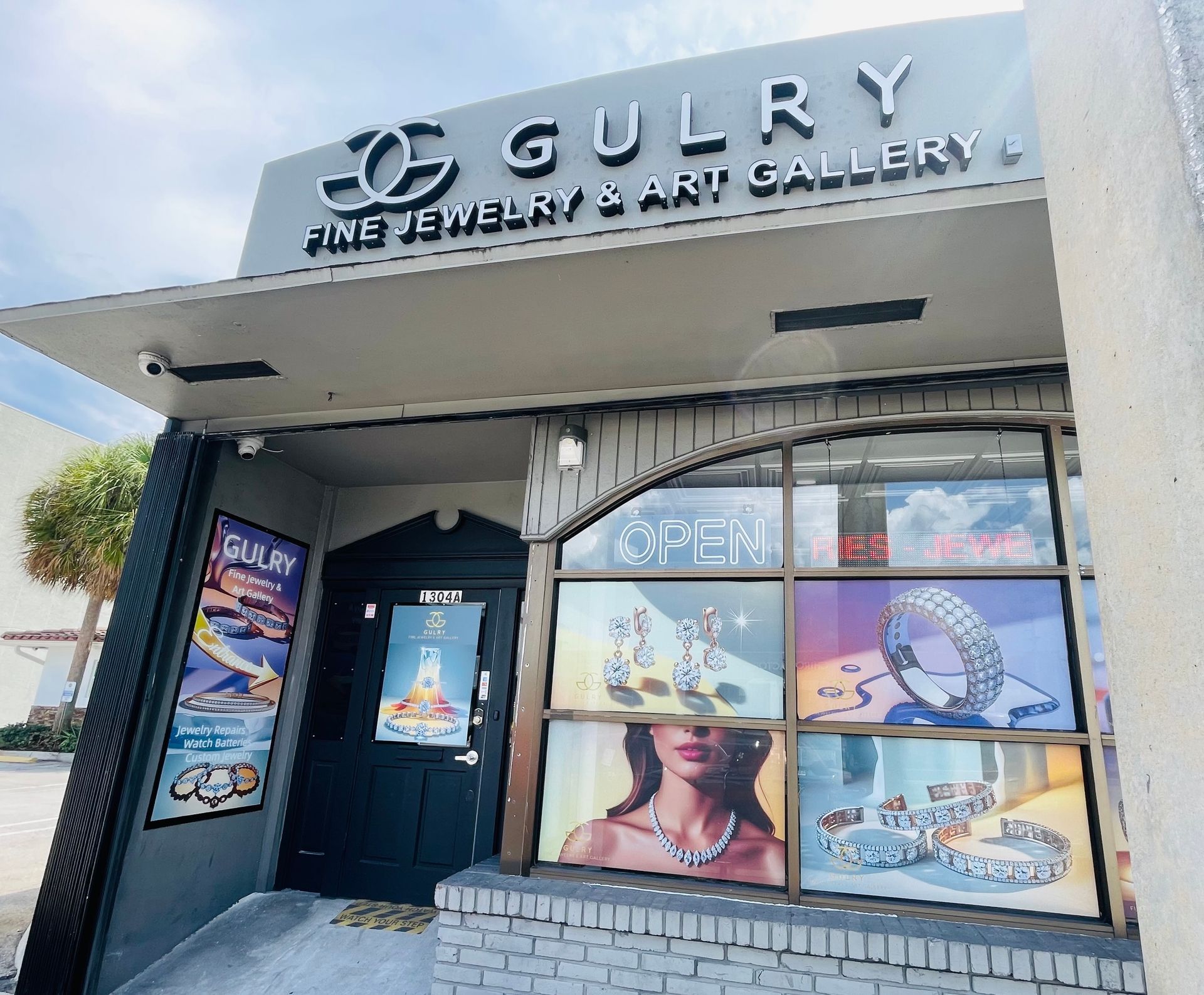 GULRY Fine Jewelry & Art Gallery storefront with jewelry displays in windows, black door, and a gray awning.