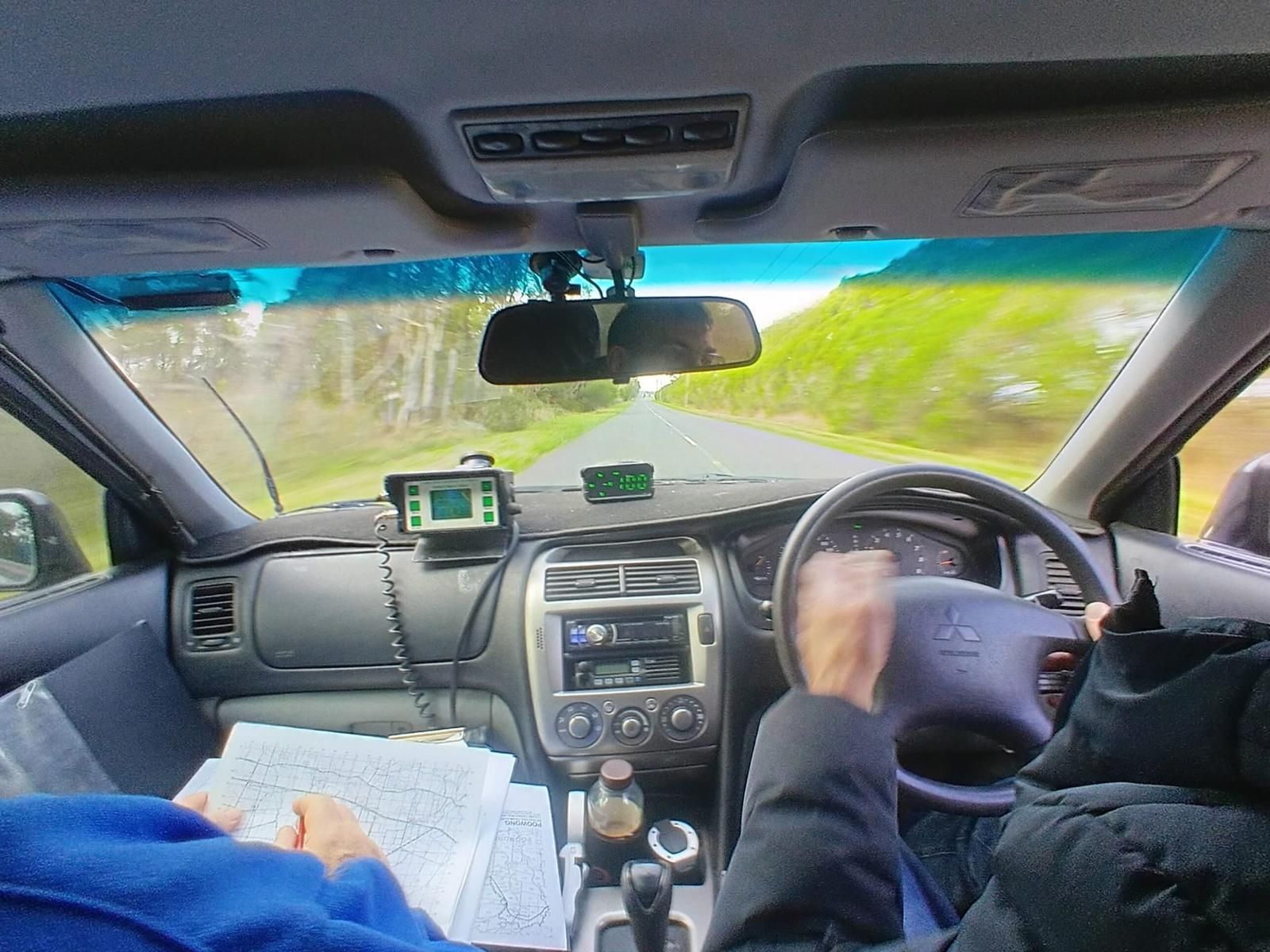 Interieurbeeld van een rijdende auto. De handen van de bestuurder aan het stuur. Dashboard met GPS zichtbaar.