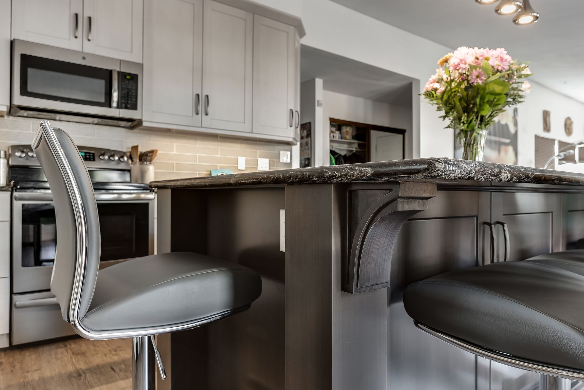 A kitchen with stools and a vase of flowers on the counter.