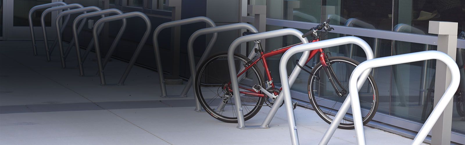 A red bicycle is parked in a row of white bike racks.