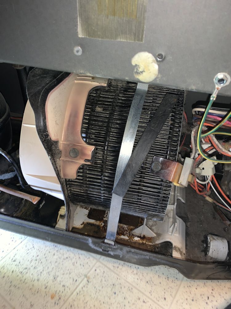 The inside of a refrigerator with the door open and a bunch of wires coming out of it.