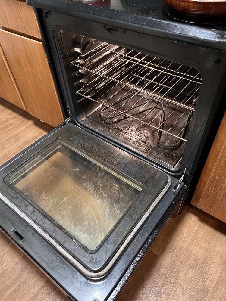 A dirty oven with the door open in a kitchen.