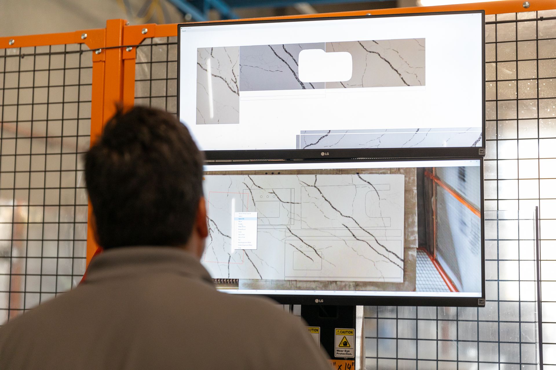 A man is pointing at a computer screen while sitting at a desk.