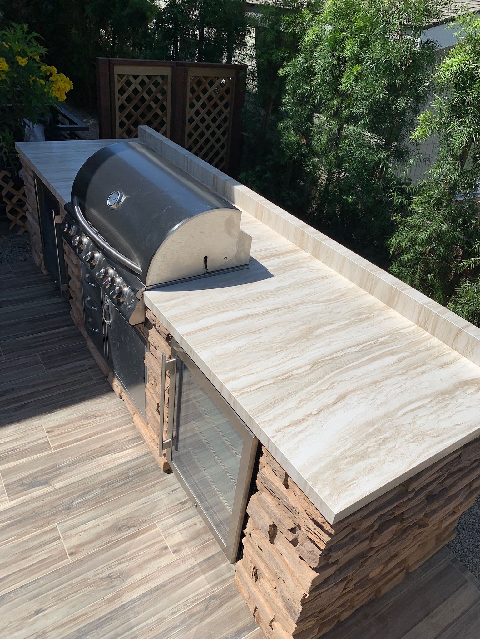 A grill is sitting on top of a granite counter on a wooden deck.