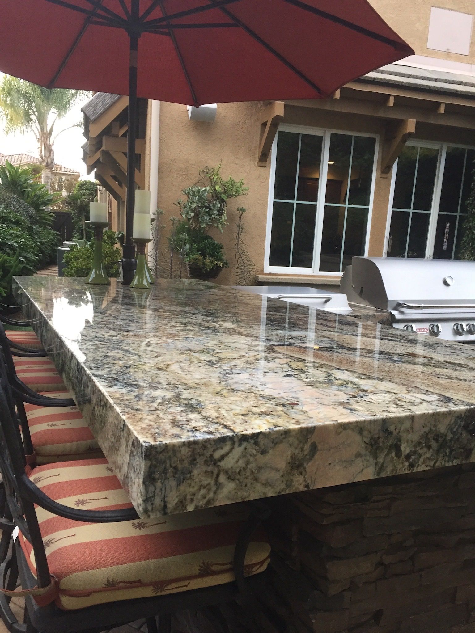 A beautiful granite table with a red umbrella on top of it