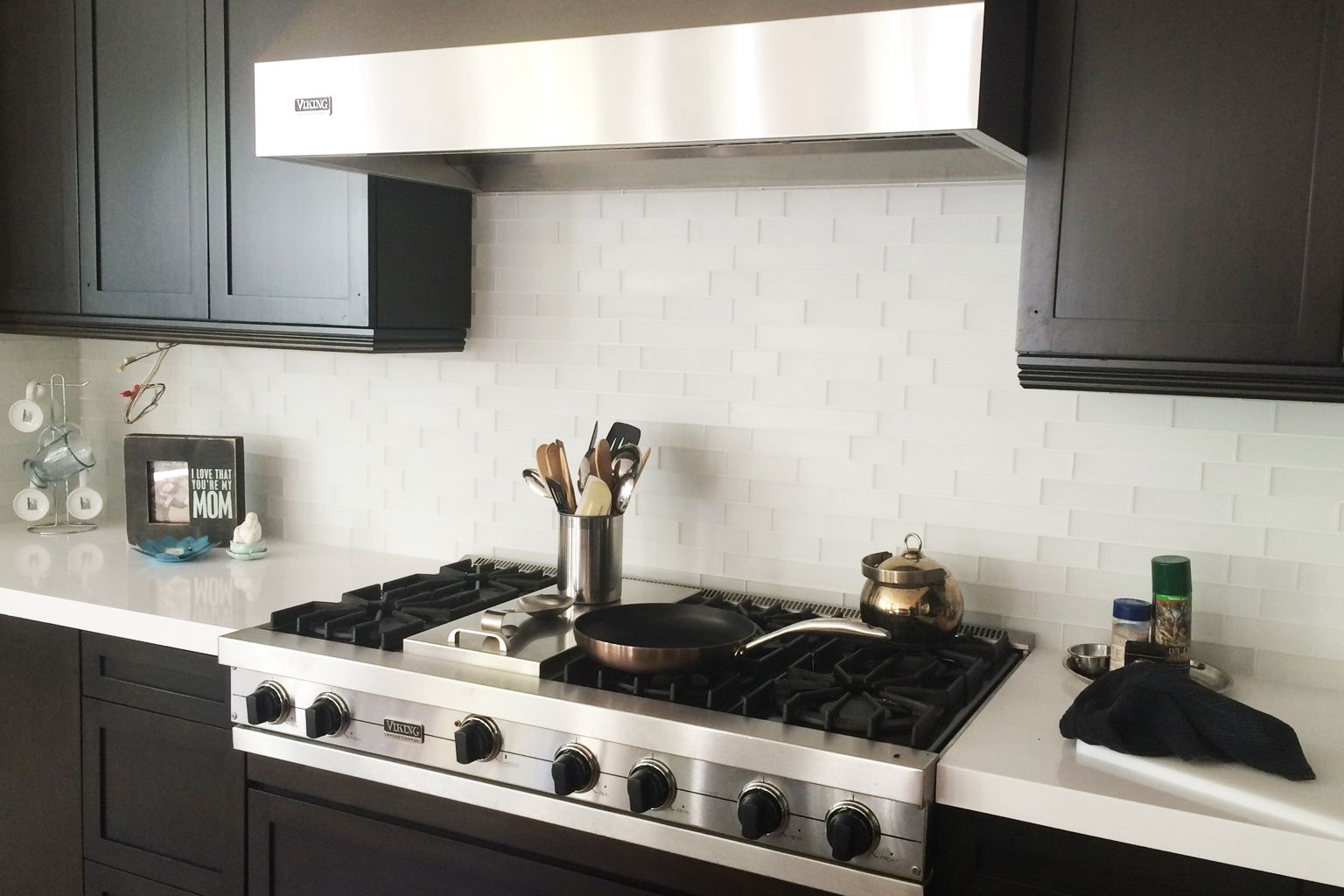 A kitchen with a stove top oven and black cabinets.