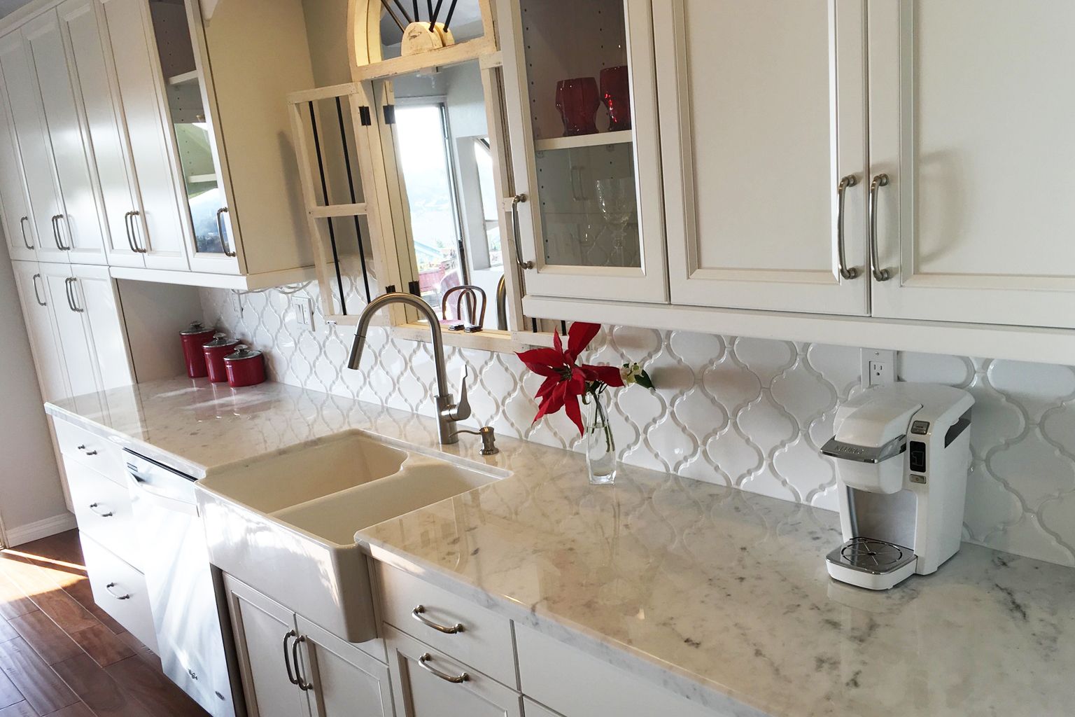 A kitchen with white cabinets , a sink , and a coffee maker.