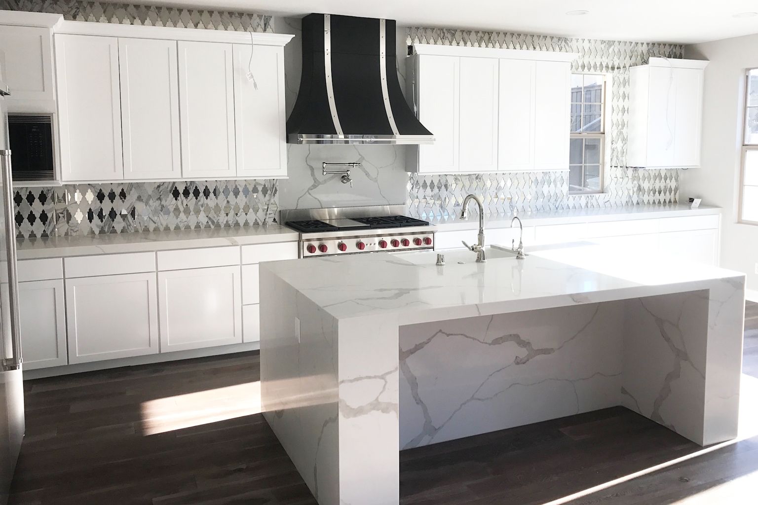 A kitchen with white cabinets and a large island in the middle