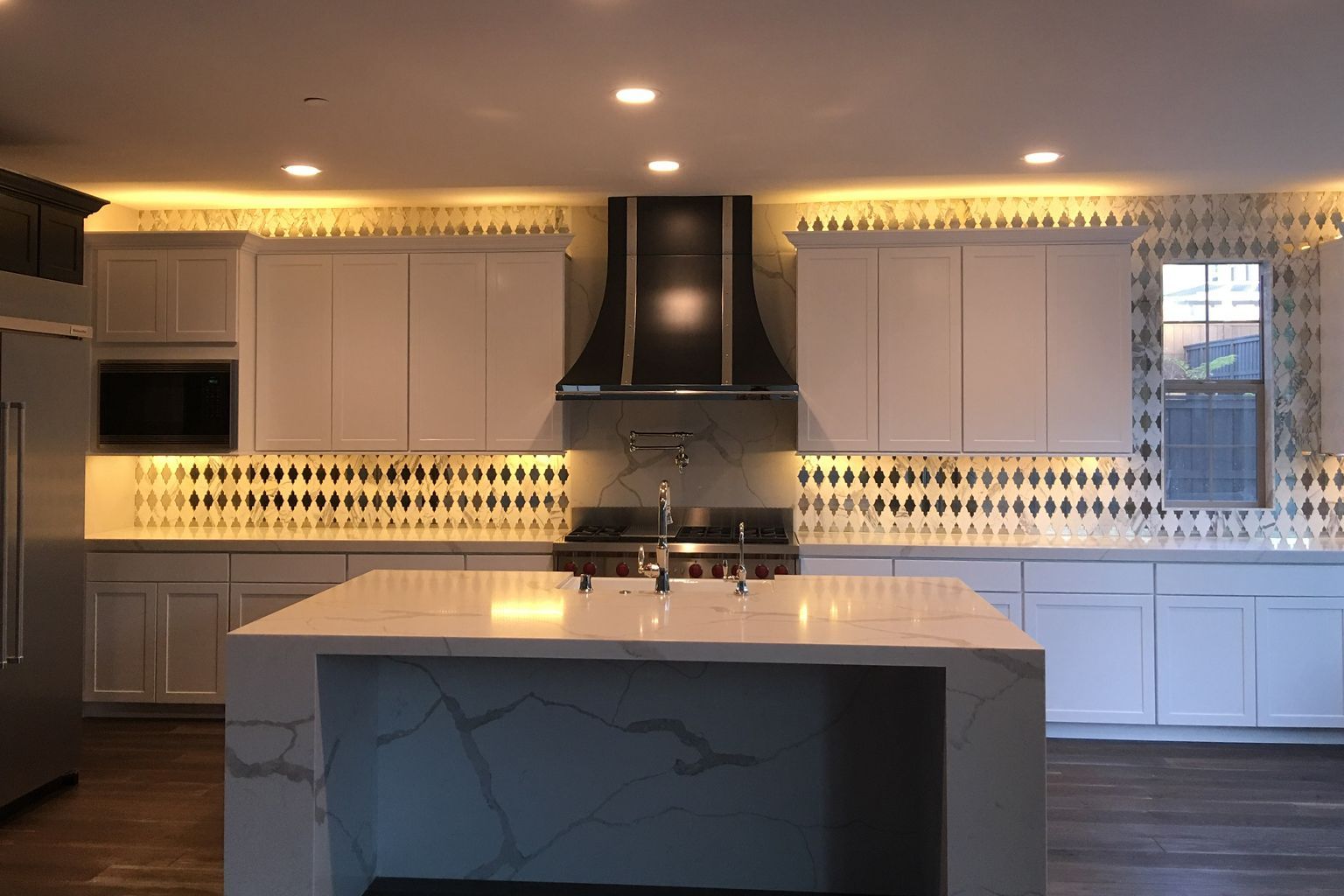A kitchen with white cabinets and a large island in the middle