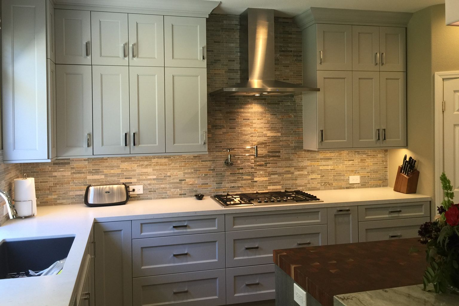 A kitchen with white cabinets and a stove top oven.