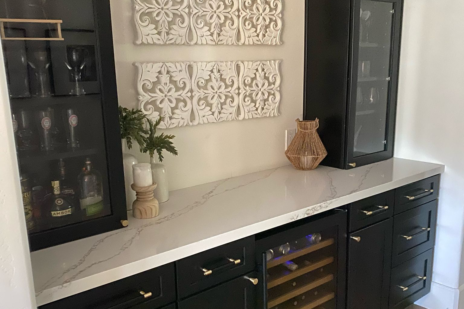 A kitchen with black cabinets and a wine cooler.