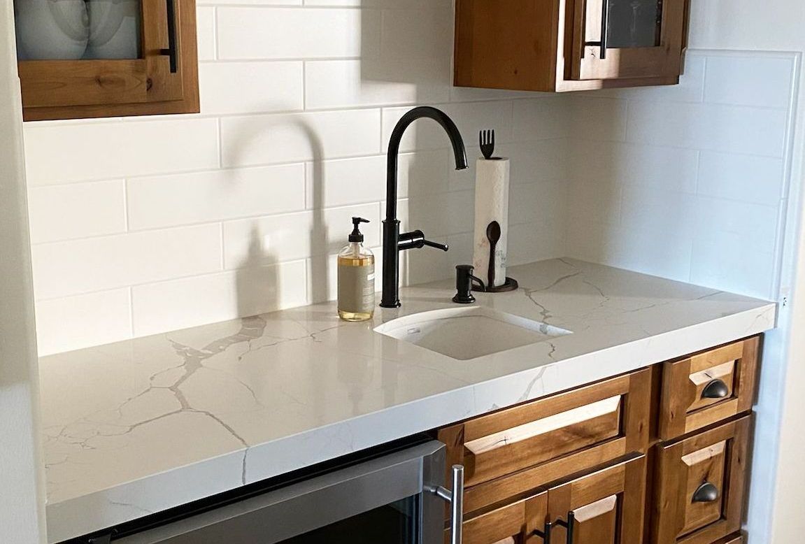 A kitchen counter with a sink , faucet and dishwasher.