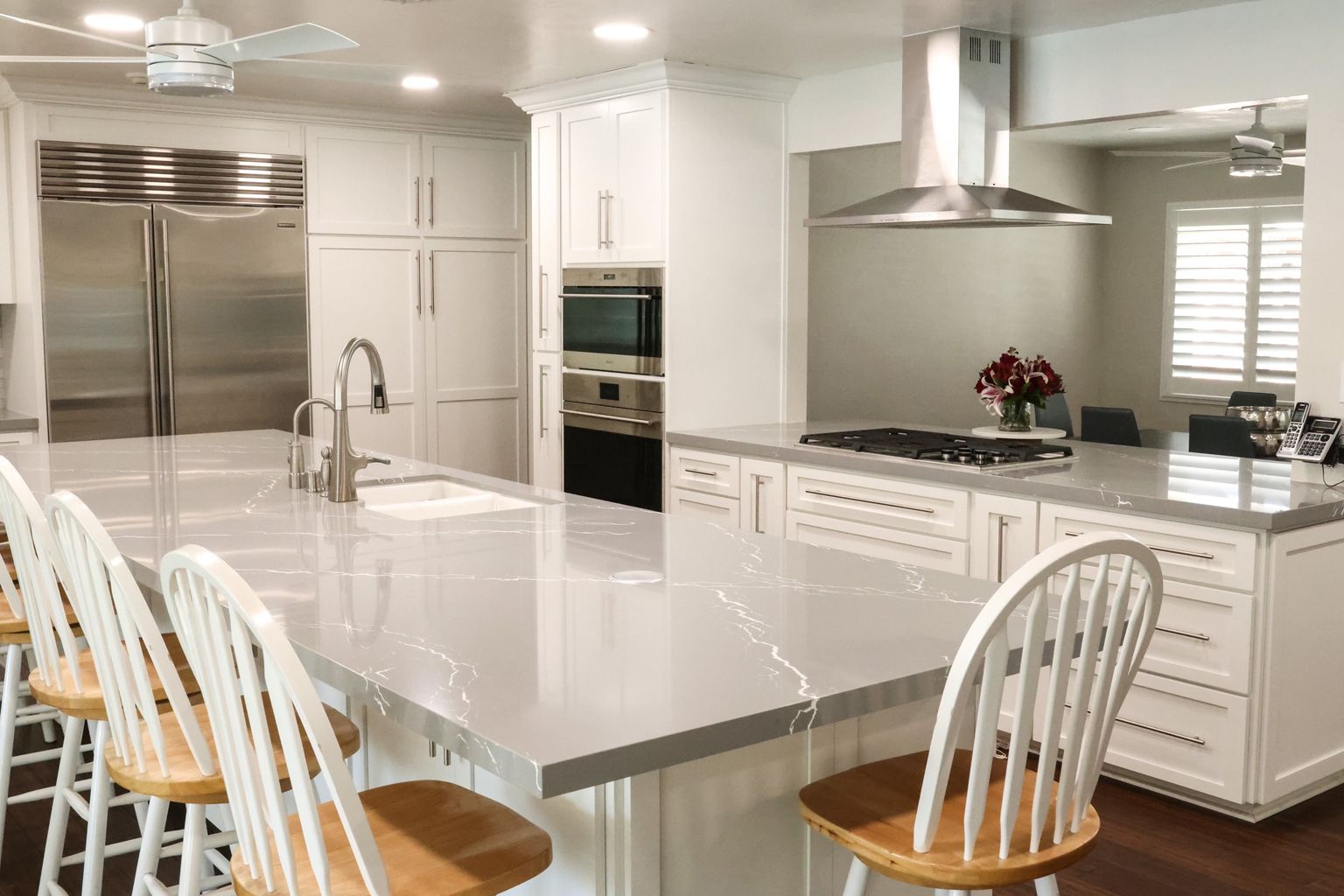 A kitchen with white cabinets and stainless steel appliances and a large island.