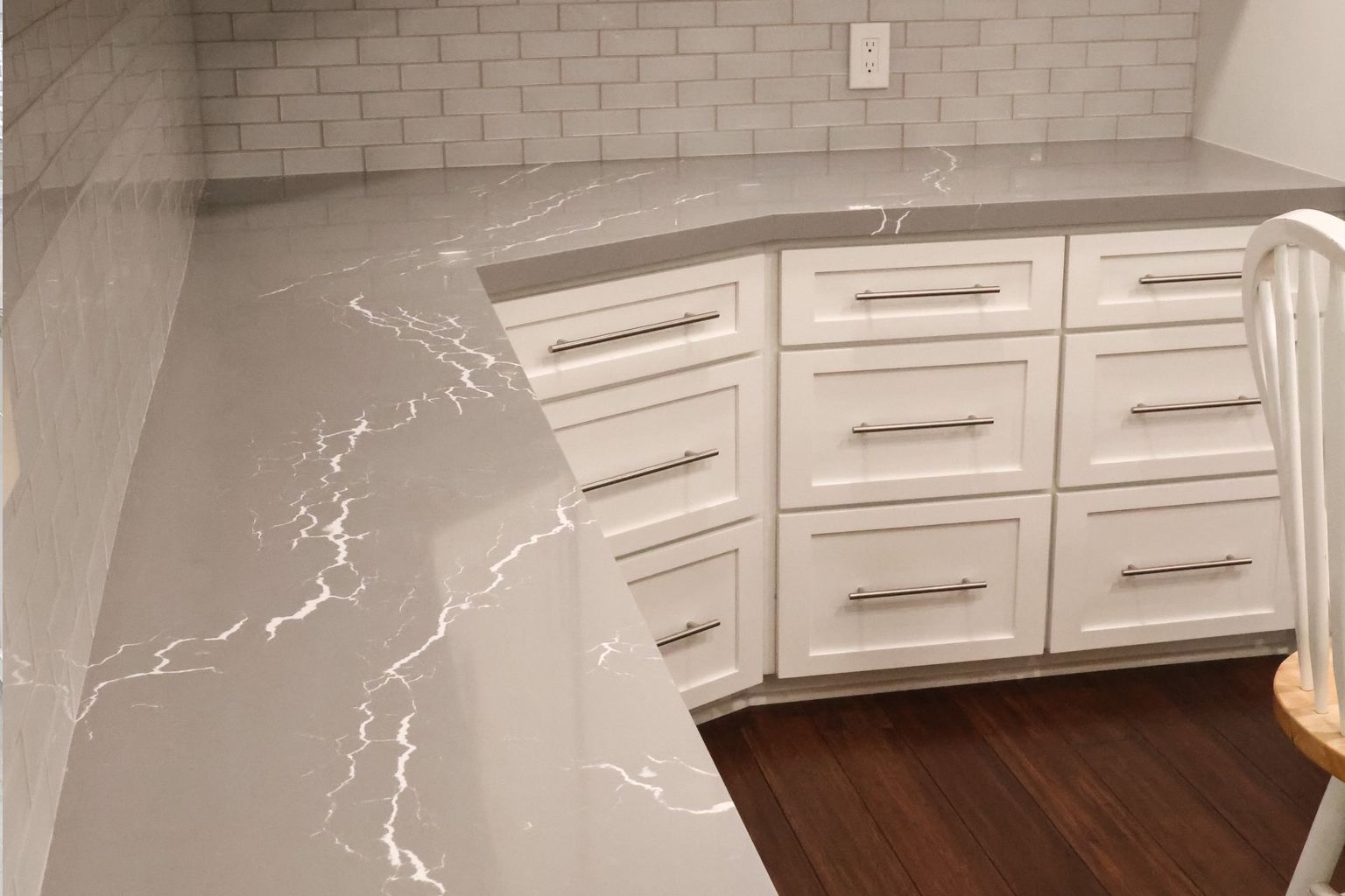 A kitchen with white cabinets and a gray counter top.