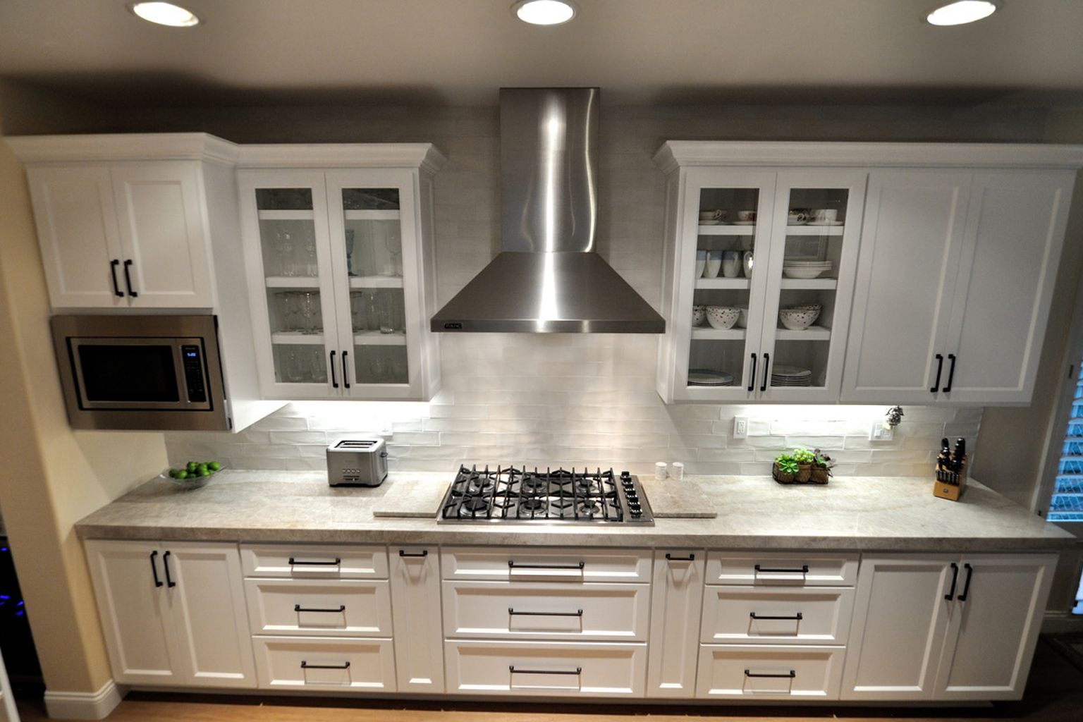 A kitchen with white cabinets and a stove top oven