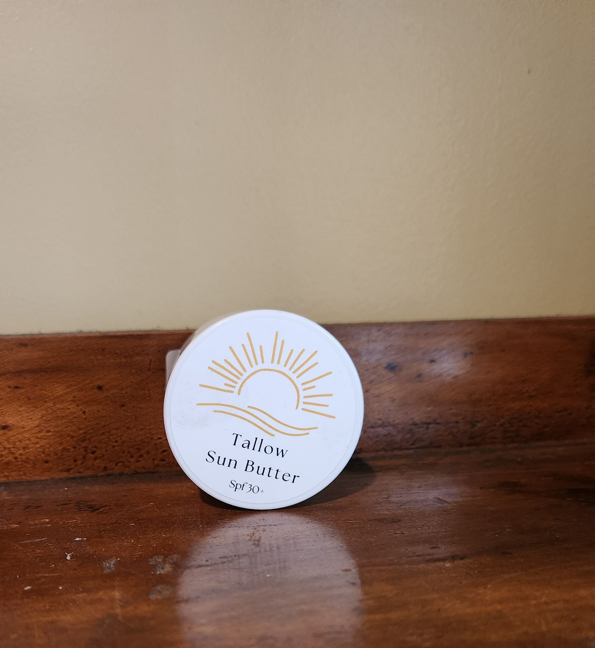 A jar of yellow sun butter sits on a wooden table