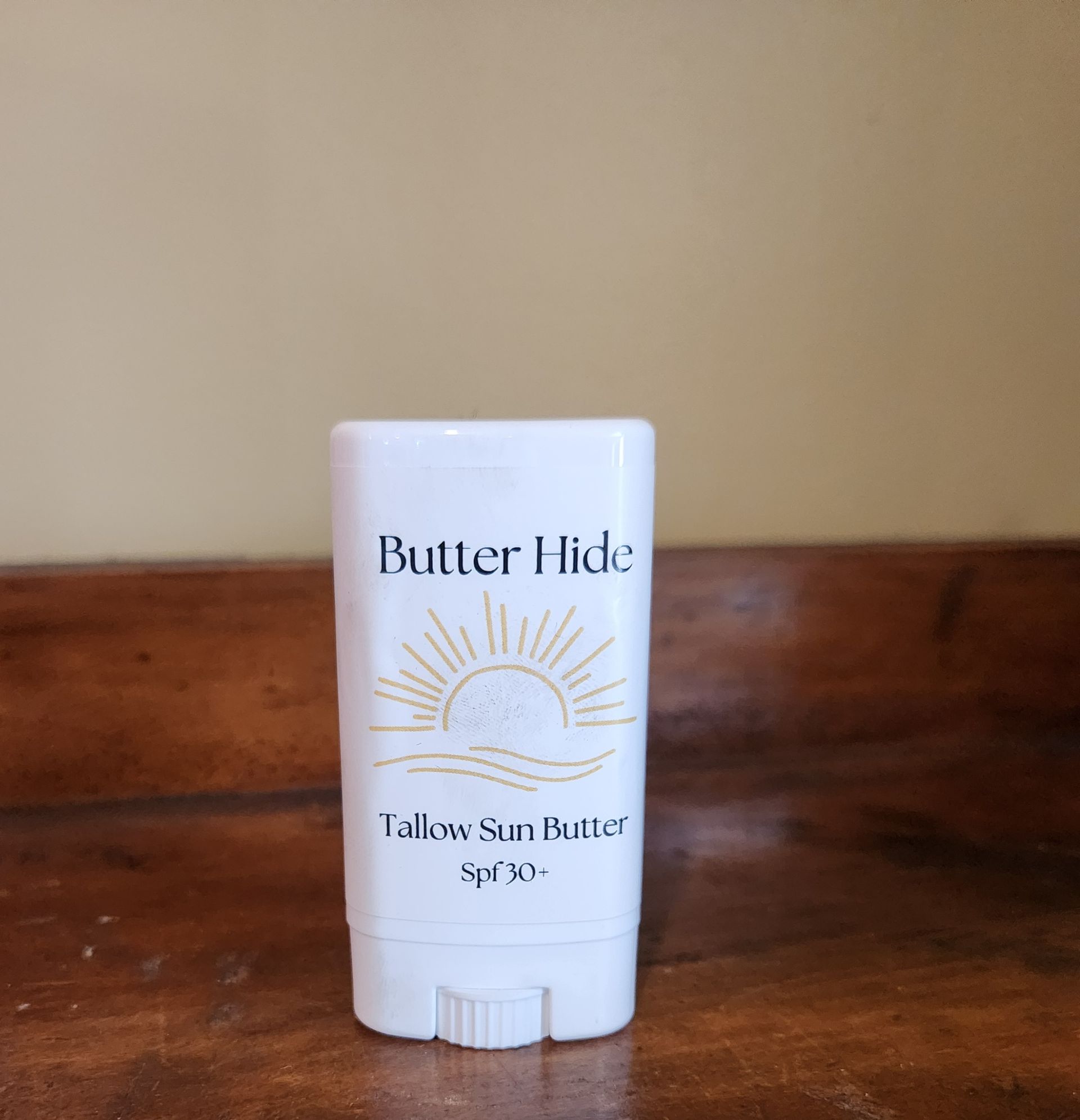 A bottle of butter hide tallow sun butter is sitting on a wooden table.