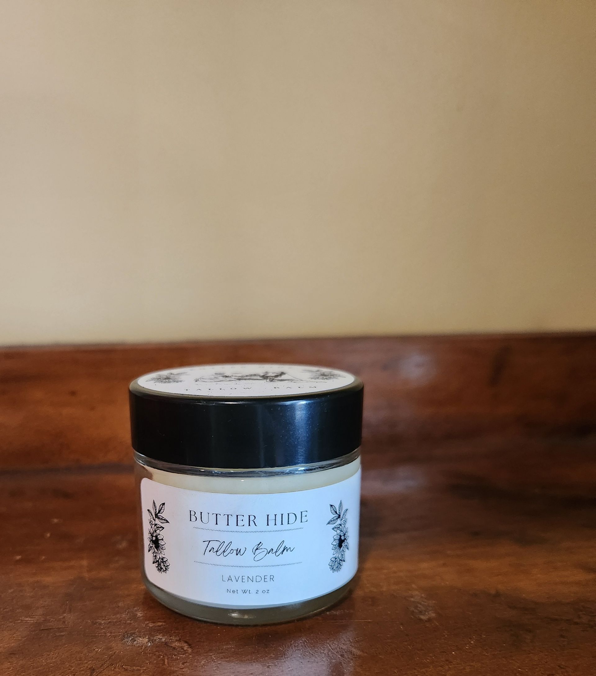 A jar of butter hide pillow balm on a wooden table