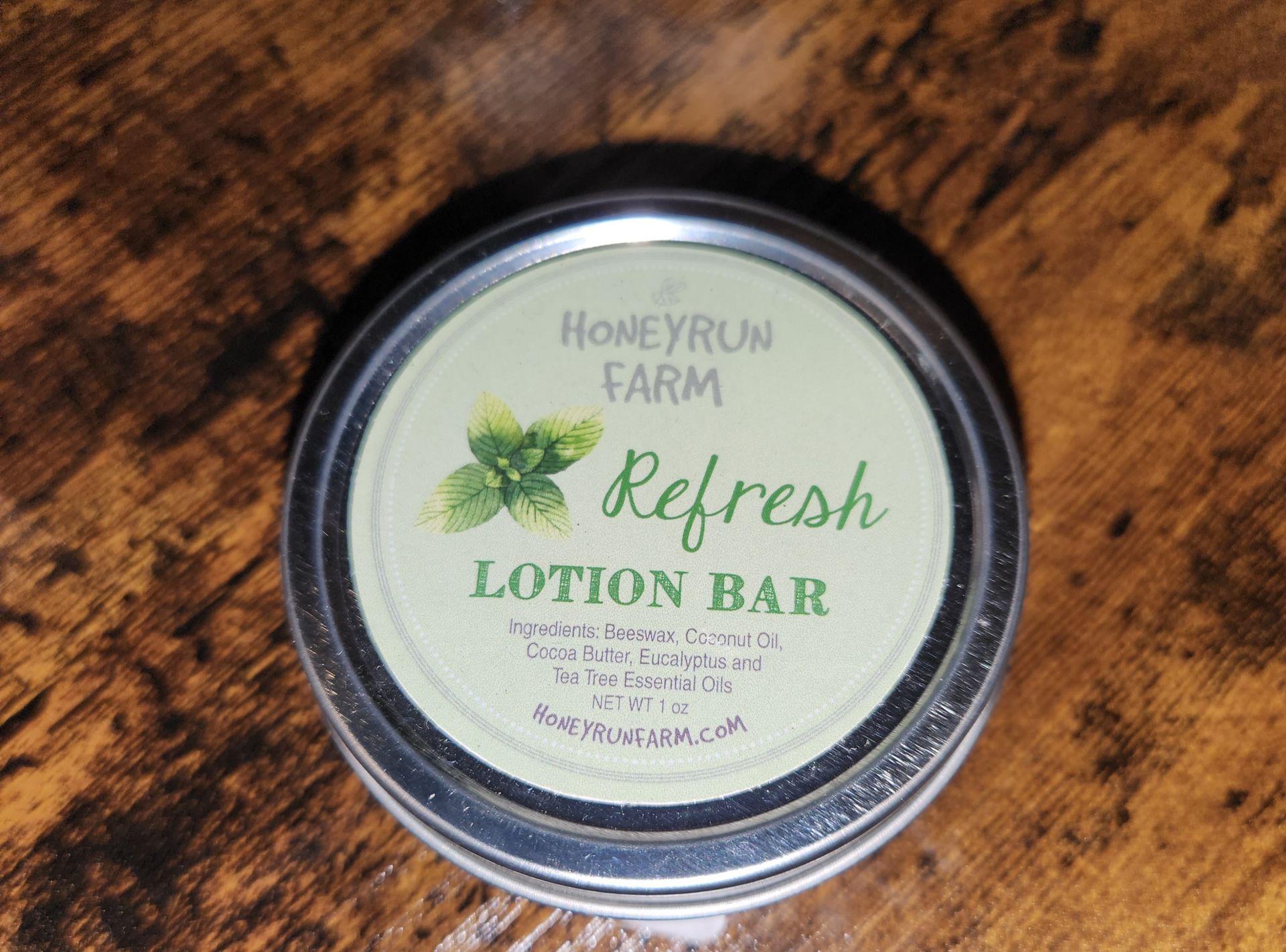 A honeyrun farm refresh lotion bar is sitting on a wooden table