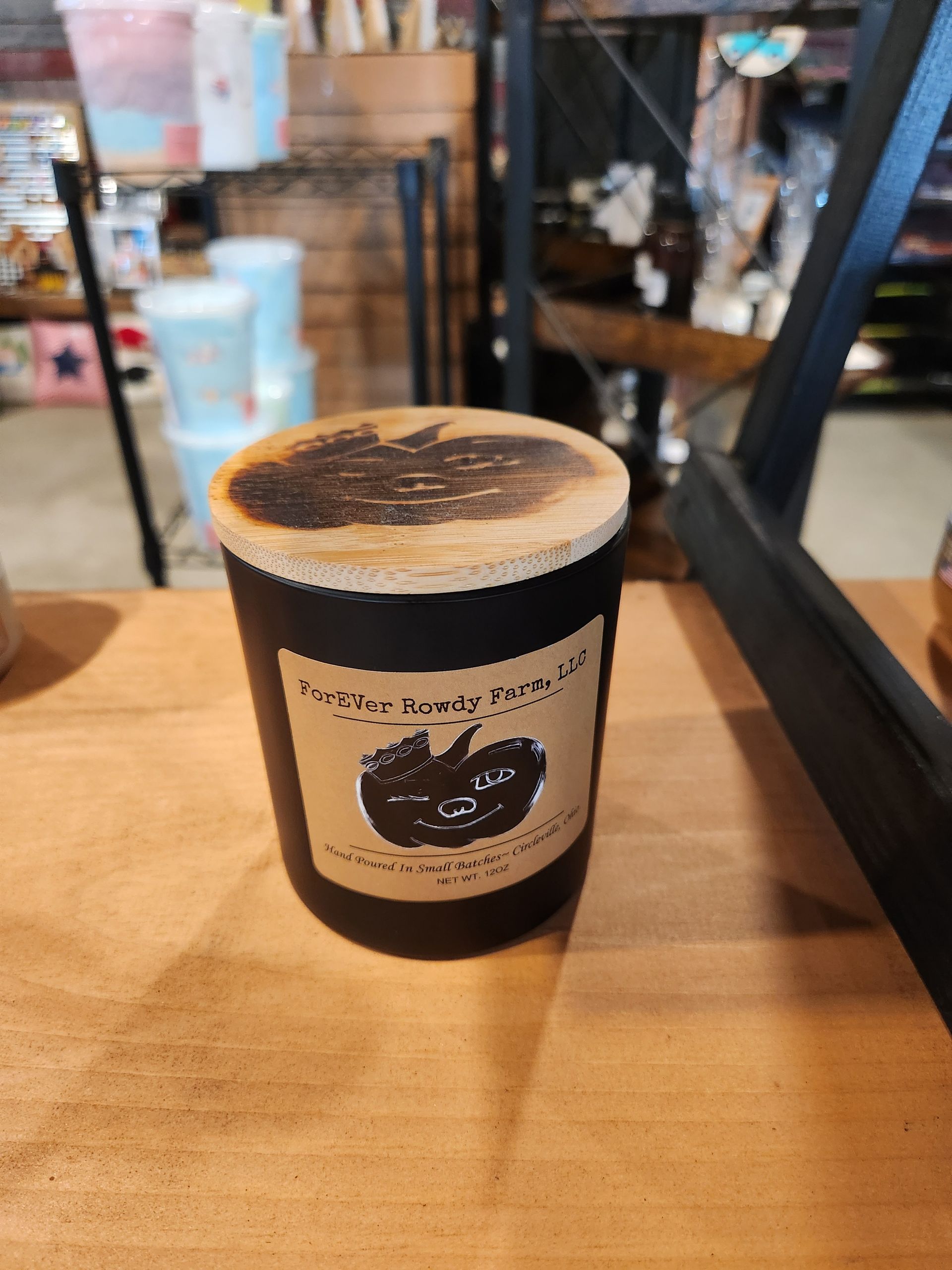 A black candle is sitting on a wooden table.