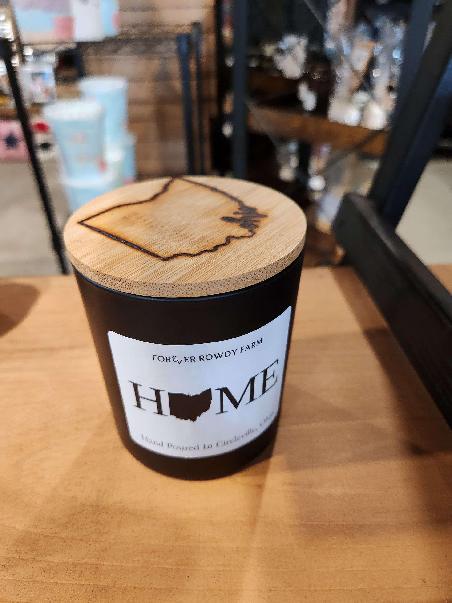 A black candle with a wooden lid that says home