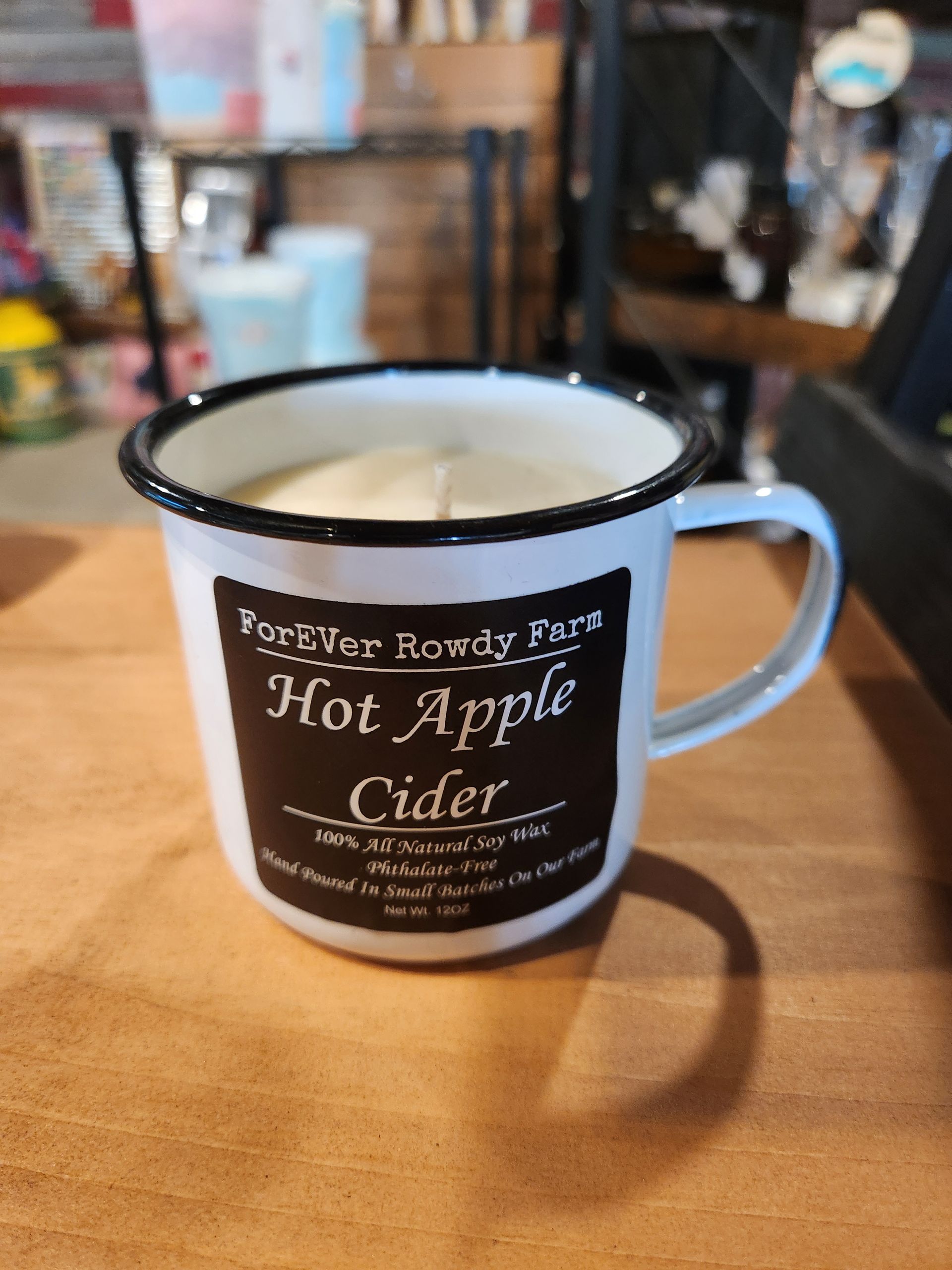 A mug of hot apple cider is sitting on a wooden table.