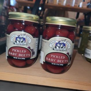 Two jars of pickled baby beets are sitting on a table