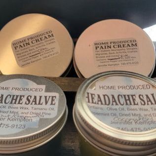 Two cans of home produced pain cream and ache salve are sitting on a table.