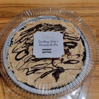 A peanut butter pie in a plastic container on a wooden table.