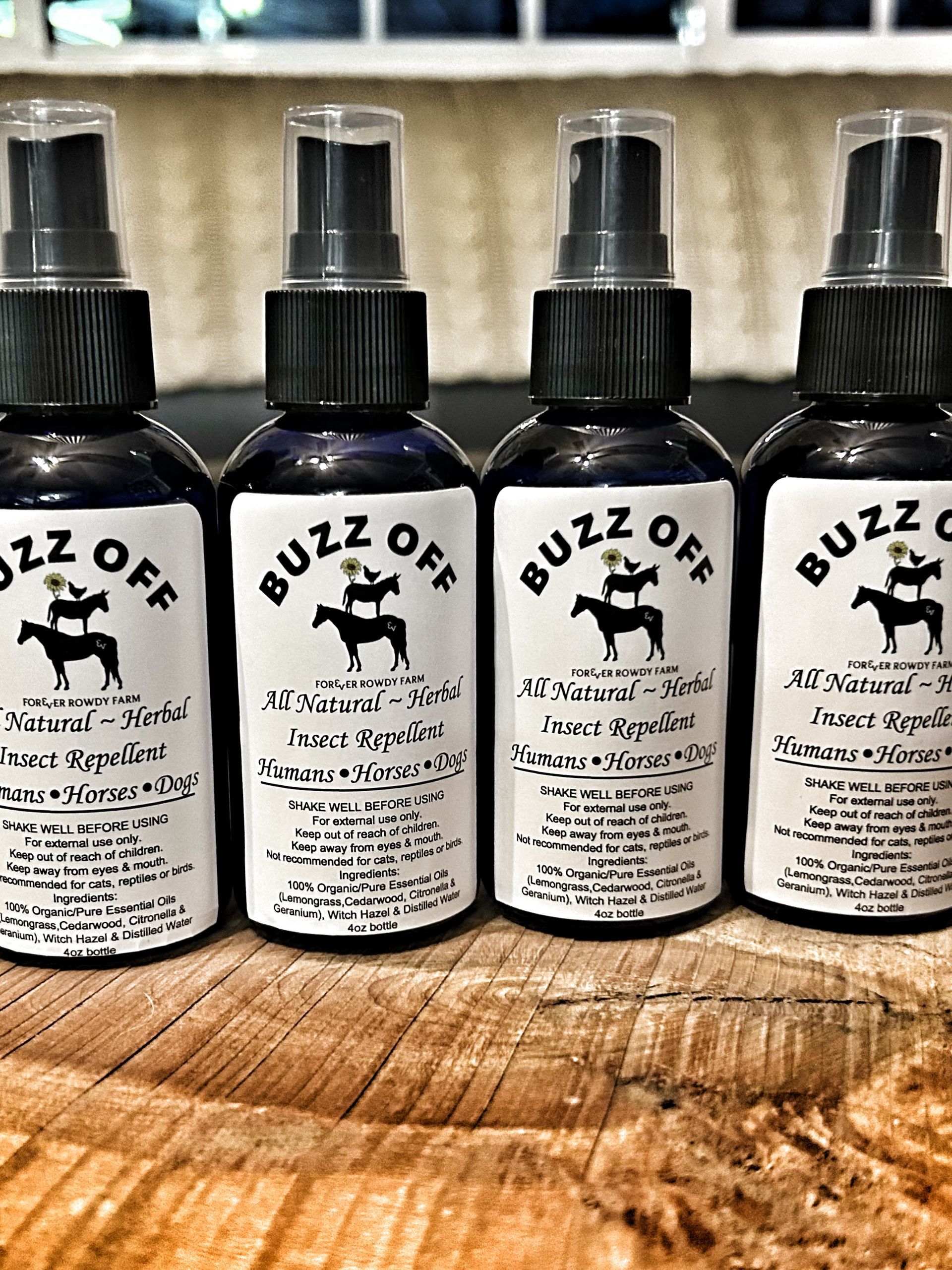 Four bottles of buzz off insect repellent are sitting on a wooden table.