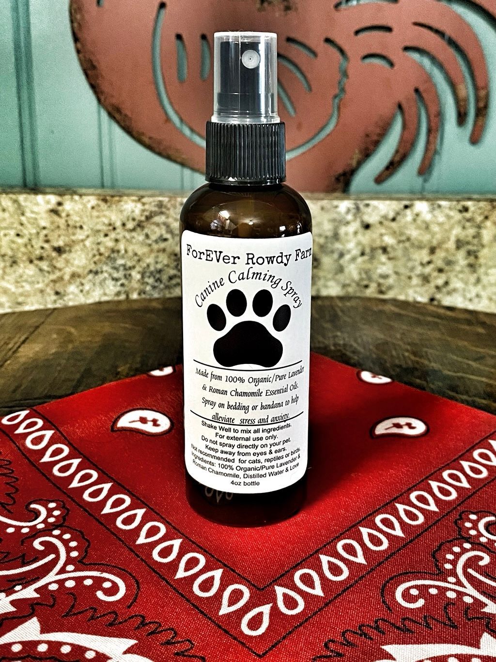 A spray bottle with a paw print on it is sitting on a red bandana.