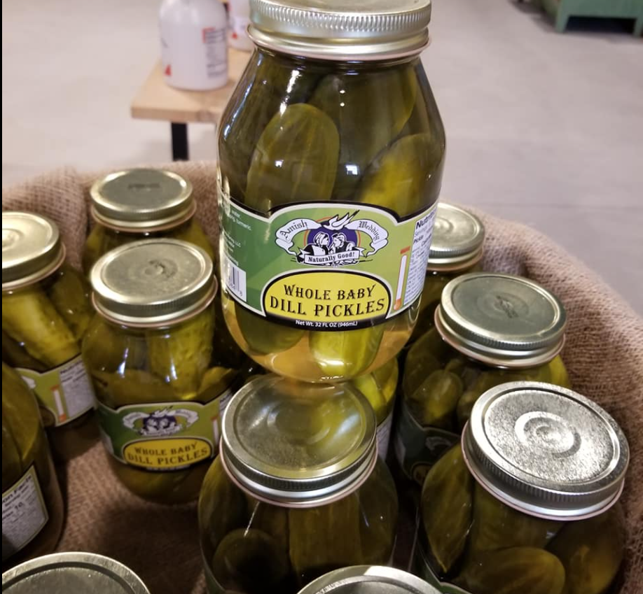 A jar of dill pickles is surrounded by other jars