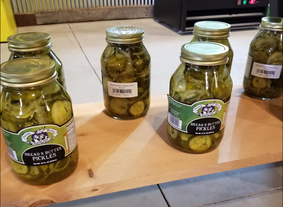 Several jars of pickles are sitting on a wooden table