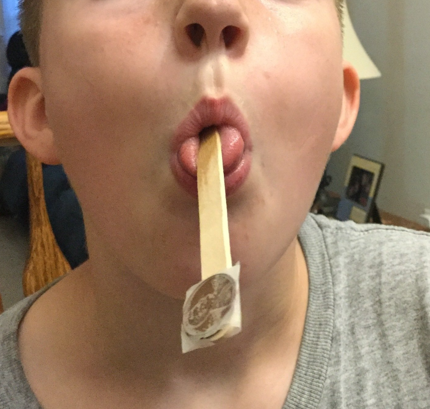 young boy mouth with popsicle stick with a penny taped to the end