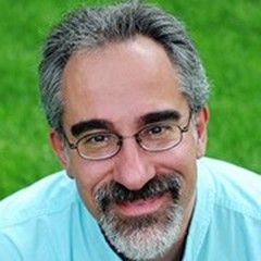 A man with glasses and a beard is smiling for the camera.
