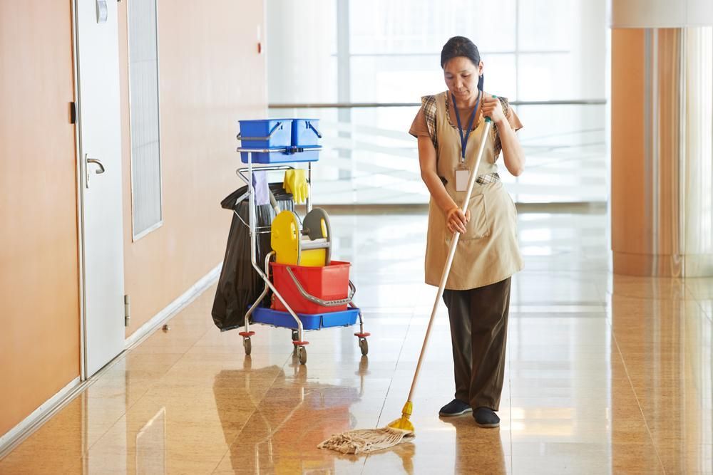 A Woman Is Mopping the Floor in A Hallway — KJ's Elite Cleaning Services Newcastle in Lake Macquarie, NSW