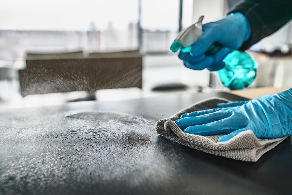 A Person Wearing Blue Gloves Is Cleaning a Table — KJ's Elite Cleaning Services Newcastle in East Maitland, NSW