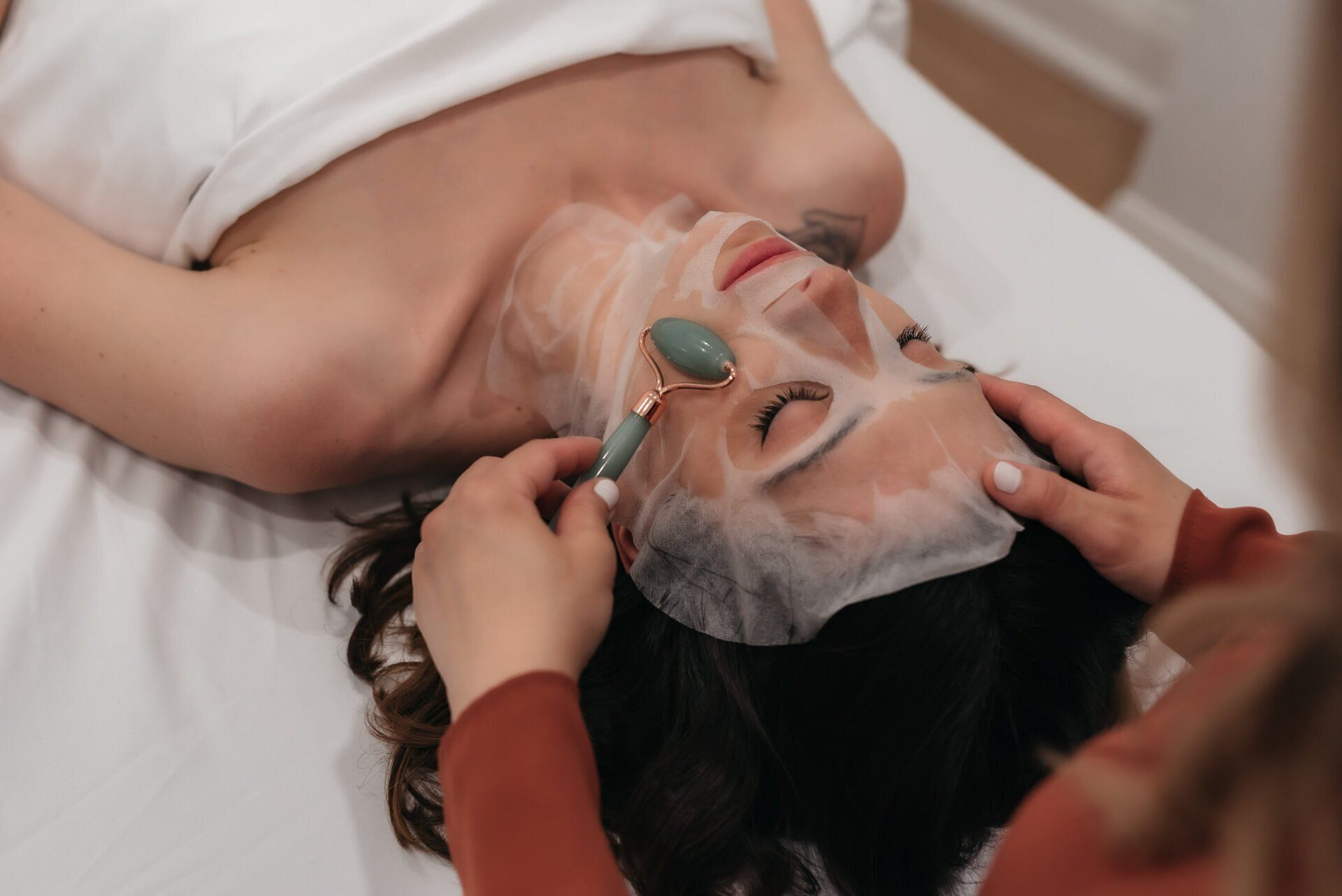 A woman receiving a facial treatment while lying on a spa treatment table