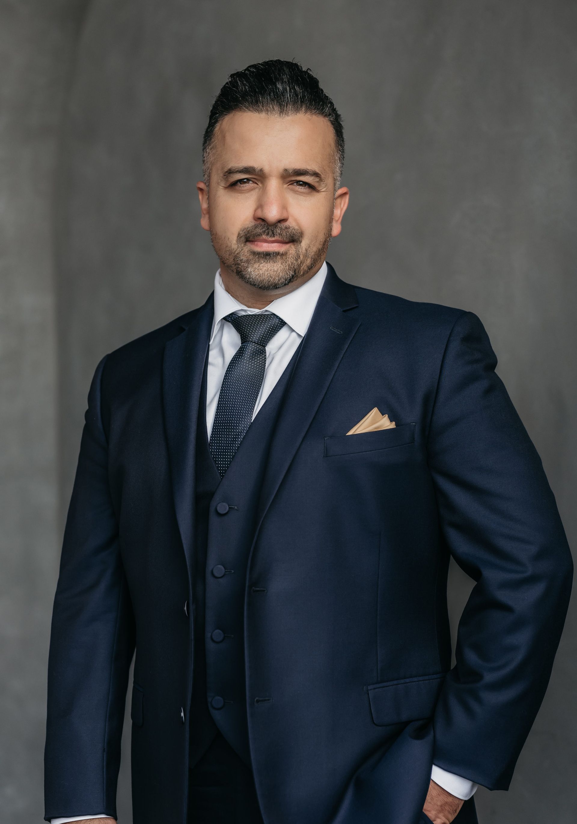 A man in a suit and tie is standing with his hands in his pockets.