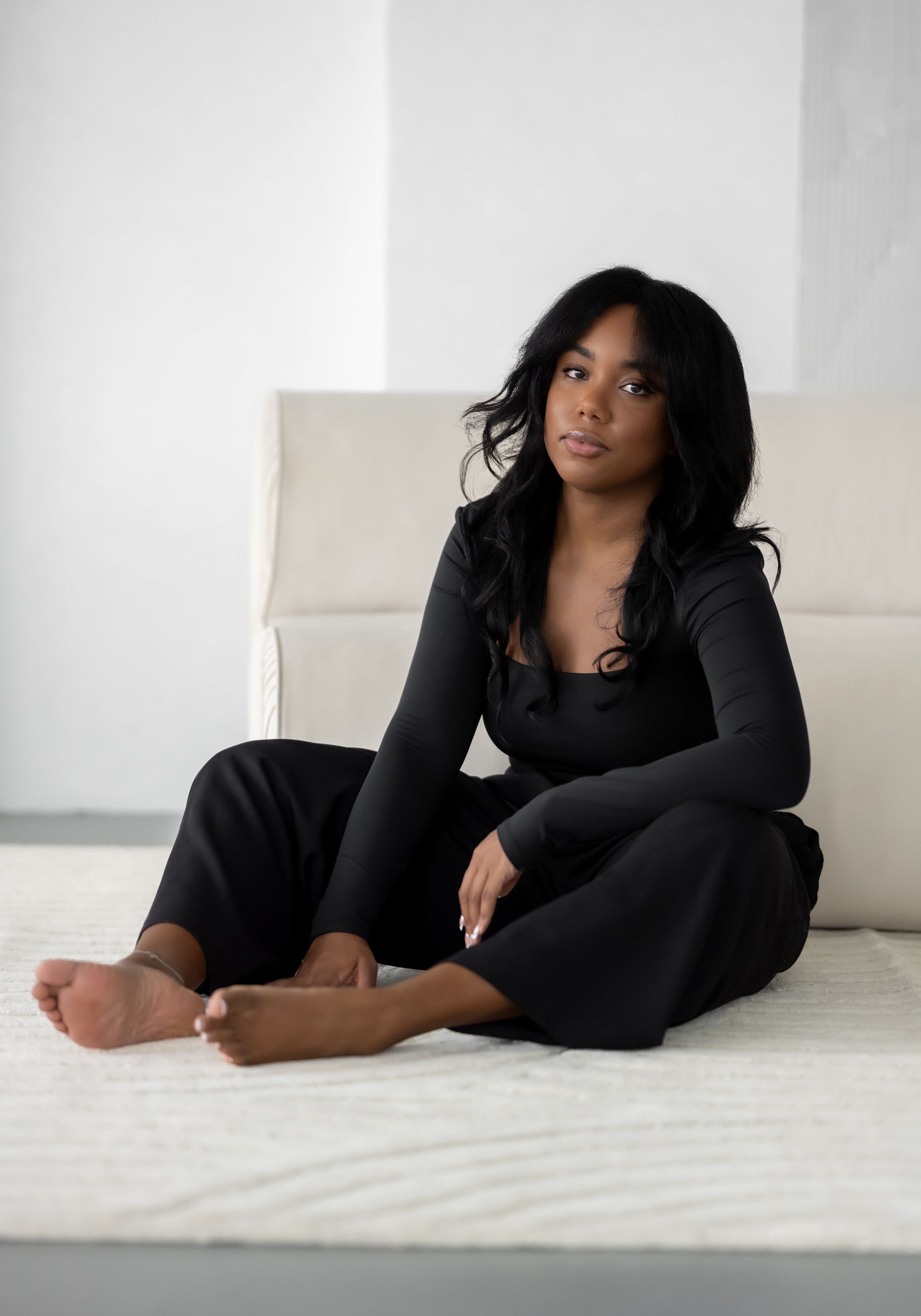 A woman in a white suit is sitting on a white couch.