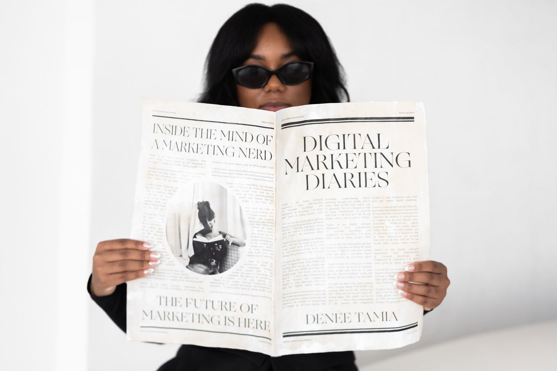 A woman wearing sunglasses holds up a newspaper featuring the headline 
