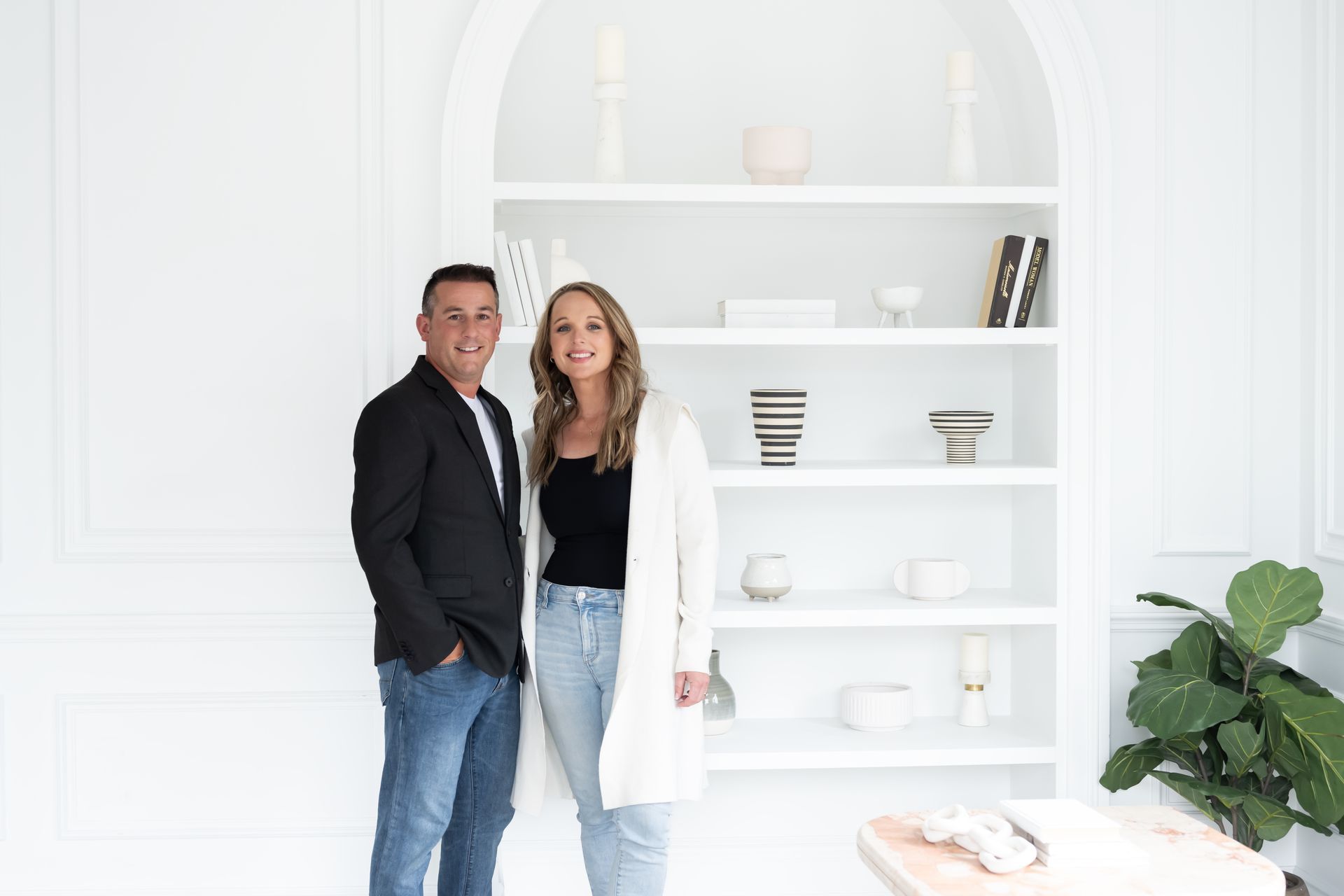 A man and a woman are standing next to each other in front of a bookshelf.