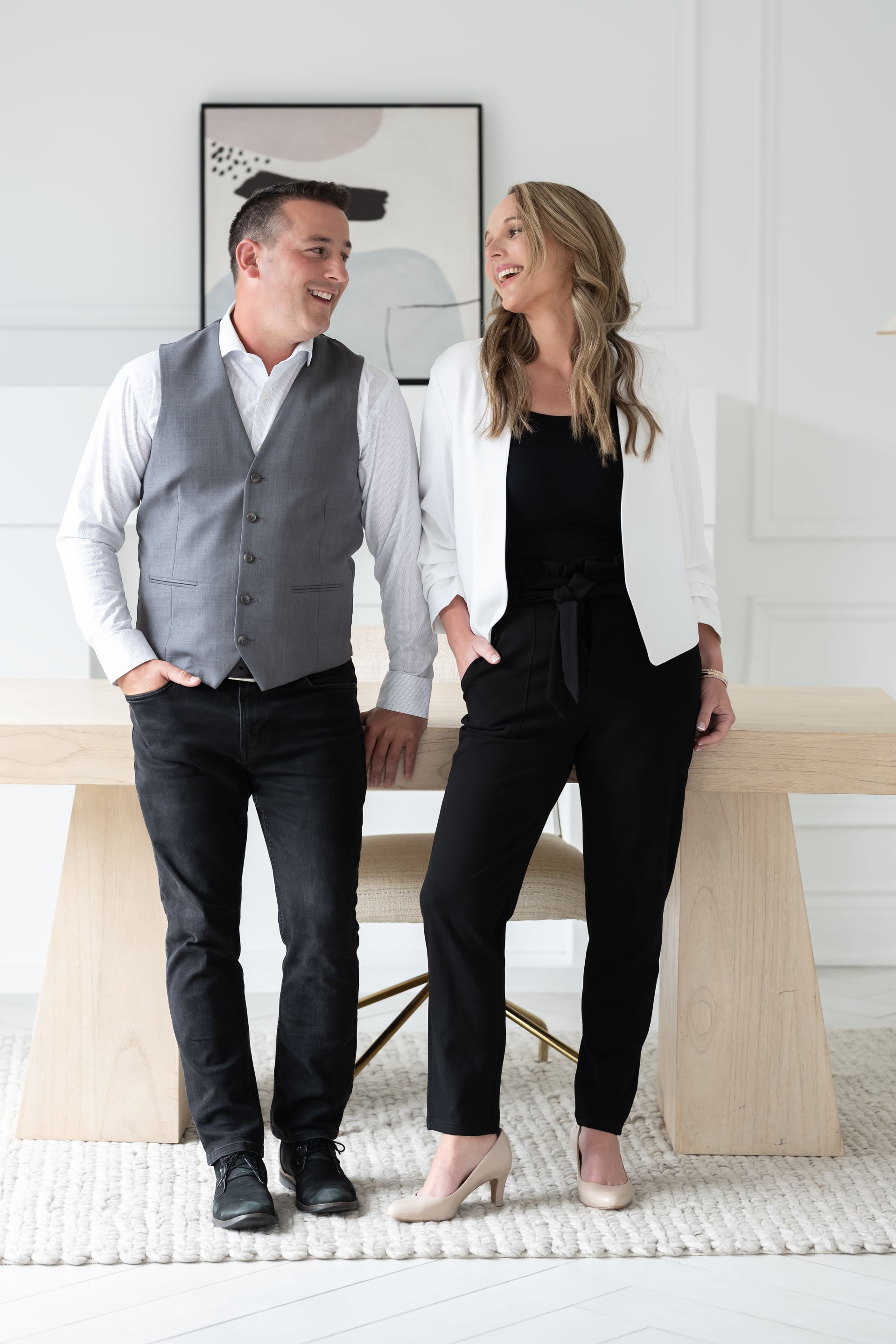 An informal and cozy portrait of a smiling couple seated on a white couch, conveying a relaxed yet professional ambiance.