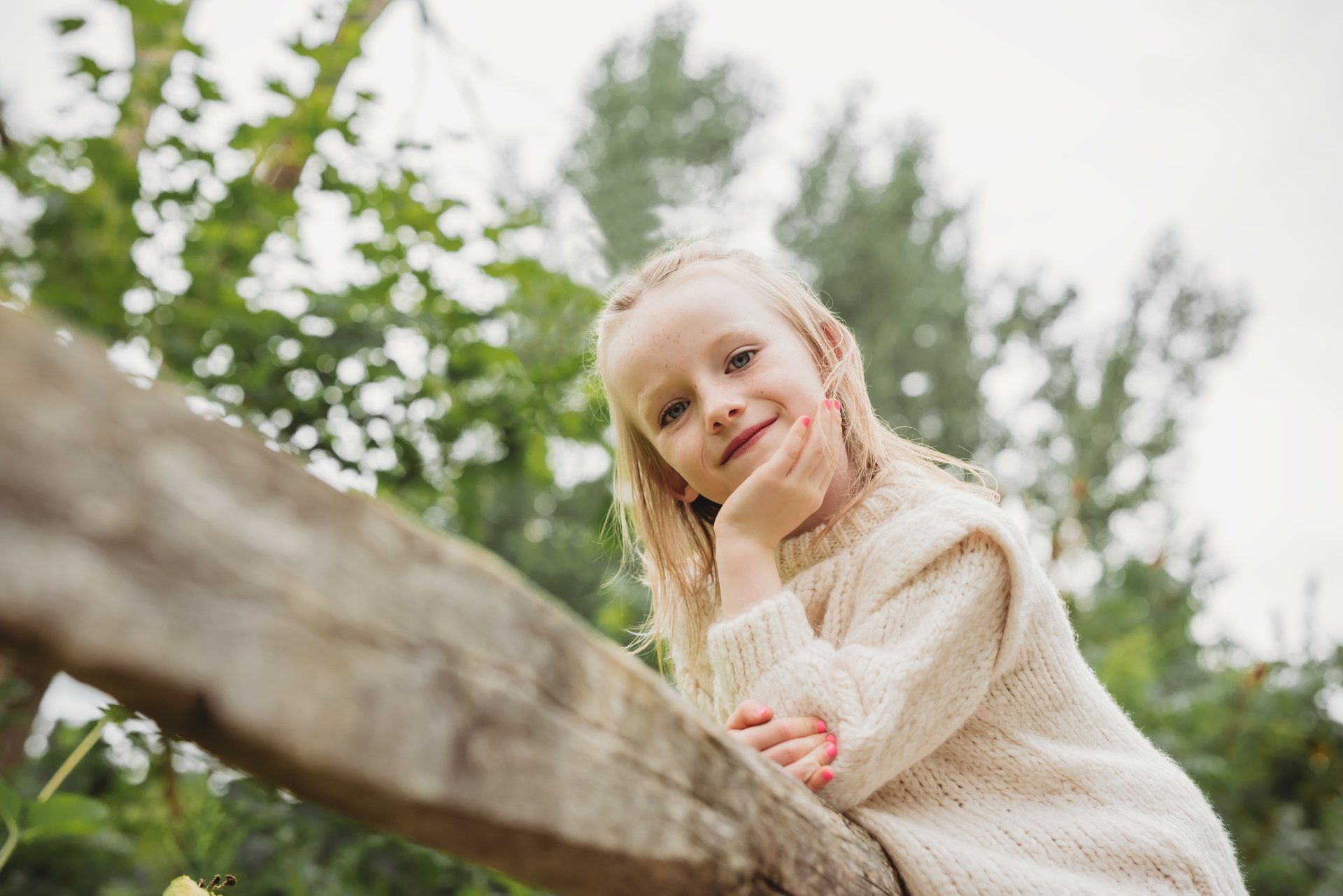 young girl leaning against a wooden fence