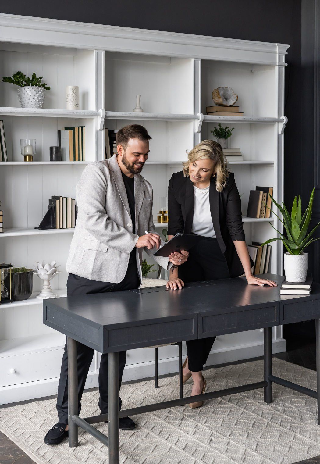 A man and woman stand at a desk, collaborating over a laptop in a modern office setting.